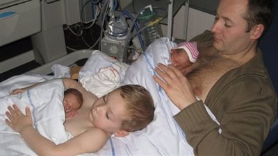 Young boy helps dad to keep his newborn twin siblings warm in viral photo